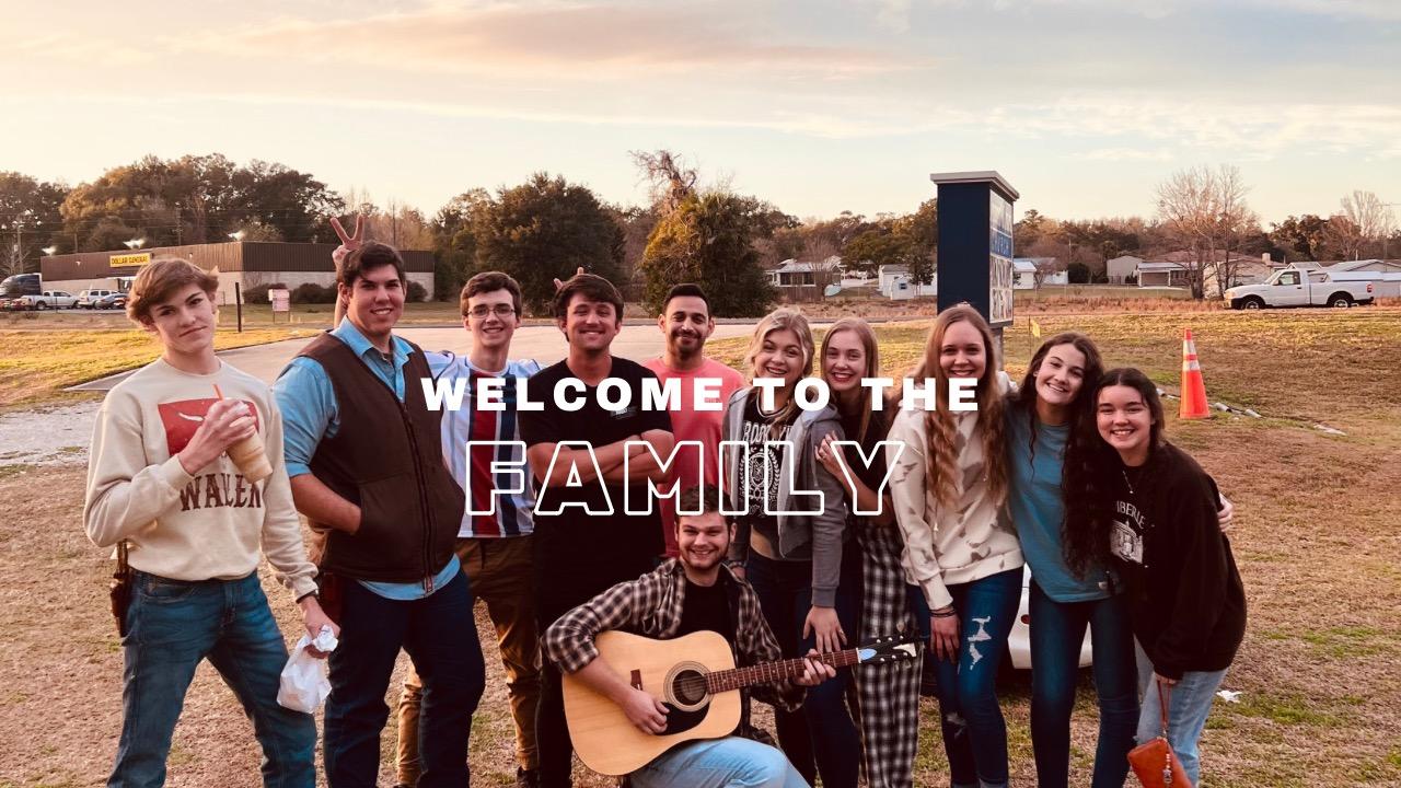 A Youth Group Gathers Arm and Arm with a Guitar. The Words "Welcome to the Family" Are on Top of the Image